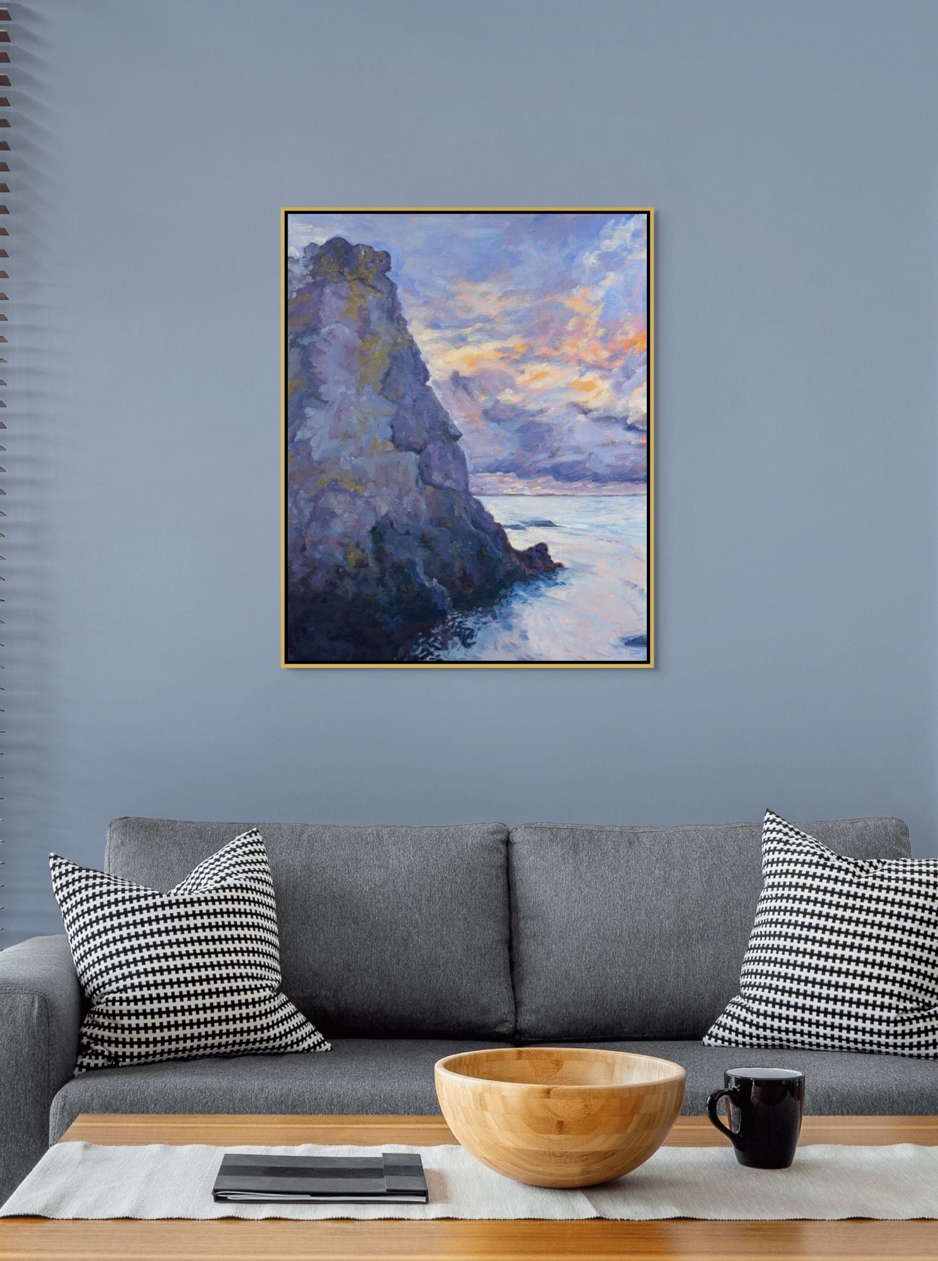 Stone Giant oil painting by Sally Herriott, solitary rauk sea stack rising from calm Baltic water at sunset, displayed in a blue Scandinavian lounge with easy sofa